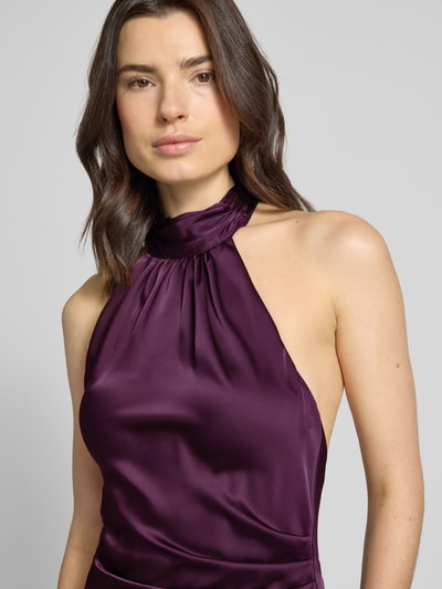Frauenmodel trägt Regular Fit Abendkleid mit Raffungen von Jake*s Cocktail aus violettem Satin, Halterneck, Rückenausschnitt, ärmelloses Design, Nahaufnahme Oberkörper.