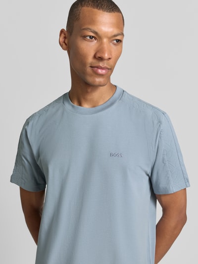Mannenmodel draagt Regular Fit t-shirt van katoenmix model 'TS_Union Tape' van BOSS Green in lichtblauw, detailopname bovenlichaam.