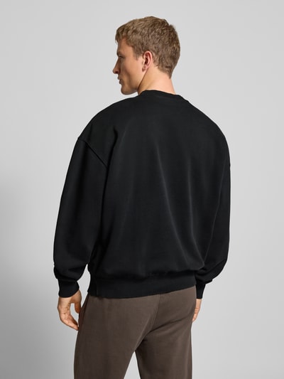 Mannelijk model draagt Oversized Sweatshirt met Labelstitching van Pegador, katoenmix, ribboorden, ronde hals, ruglengte maat M 71 cm, oversized, geribbelde textuur, donkere tinten, rugaanzicht volledige lichaamsopname.