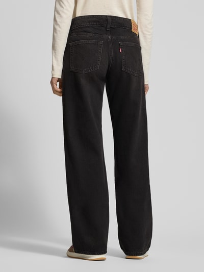 Frauenmodel trägt Superlow Loose Fit Jeans mit Eingrifftaschen von Levi's®, gerade Form, schwarze Baumwolle, Ganzkörperansicht Rückansicht.