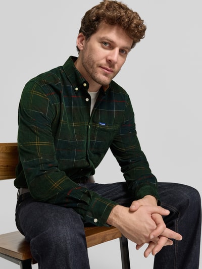 Męski model nosi Tailored Fit Flanellhemd mit Brusttasche od Barbour, zielony, kraciasty, długi rękaw, kołnierzyk button-down, kieszeń na piersi, materiał sztruks, wygląd wielokolorowy, casualowa koszula, widok na górną część ciała z przodu