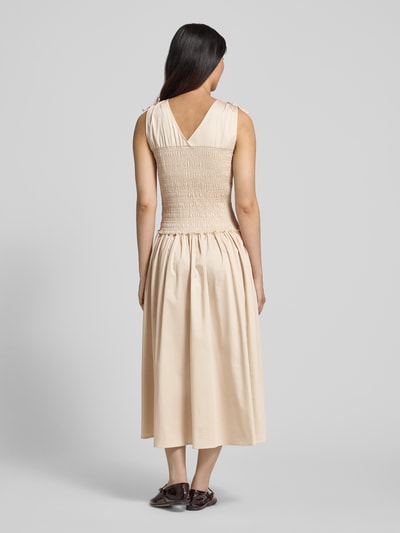 Frauenmodel trägt Midikleid mit Smok-Detail von Comma, cremefarben, Baumwoll-Mix, Taillierte Passform, Ärmelloses-Design, Ganzkörperansicht Rückansicht.