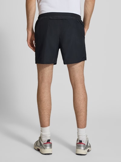 Männermodel trägt Shorts mit seitlichen Eingrifftaschen und Logo-Print von NIKE TRAINING in Schwarz, Loose-Fit, elastischer Bund, Ganzkörperansicht Rückansicht. Bundweite 40 cm, Innenbeinlänge 13 cm bei Größe M.