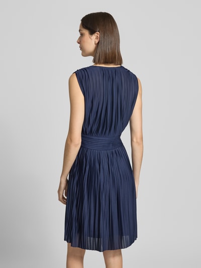 Frauenmodel trägt knielanges Cocktailkleid in Falten-Optik Modell 'Linn' von GUIDO MARIA KRETSCHMER WOMAN in Dunkelblau, Rückansicht.