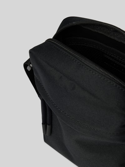 Produktfoto, schwarze Umhängetasche mit Logo-Detail Modell 'NEOCROC' von Lacoste mit sichtbarer Reißverschluss-Textur, Herren Umhängetasche