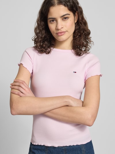 Frauenmodel trägt Slim Fit T-Shirt aus Baumwoll-Mix von Tommy Hilfiger in Rosa mit Logo-Detail, Frill-Saum, Feinripp, Nahaufnahme Oberkörper.