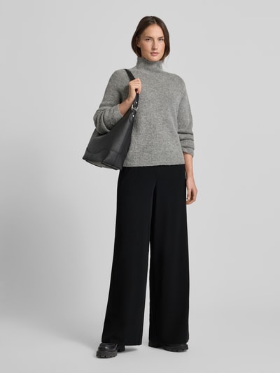 Frauenmodel trägt Wide Fit Stoffhose mit teilelastischem Bund Modell 'Coraline' von MAC, schwarze Farbe, Ganzkörperansicht von vorne. Damen Stoffhose, elastischer Material-Mix, Reißverschlusstaschen, Größe 36/32: Bundweite 38 cm, Innenbeinlänge 82 cm.
