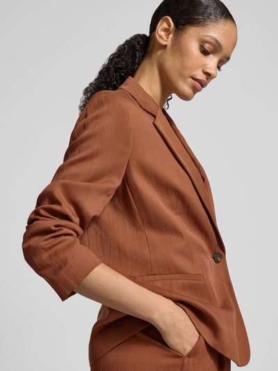 Vrouwenmodel draagt Regular Fit Blazer mit paspelzakken van Jake*s collectie in bruin met reverskraag en knoopsluiting, nahaufnahme bovenlichaam. Ruglengte maat 38: 65 cm, borstwijdte maat 38: 52 cm, mouwlengte maat 38: 43 cm.