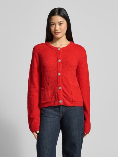 Frauenmodel trägt Strickjacke mit Knopfleiste Modell 'Hanni' von GUIDO MARIA KRETSCHMER WOMAN in Rot, gerippte Abschlüsse, Ganzkörperansicht von vorne.