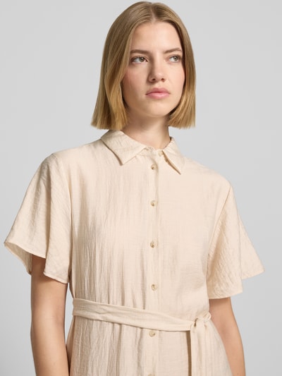 Frauenmodel trägt Midikleid aus Viskose-Mix mit Umlegekragen von COMMA in Beige, sichtbare Knopfleiste, abnehmbares Taillenband, Nahaufnahme Oberkörper.