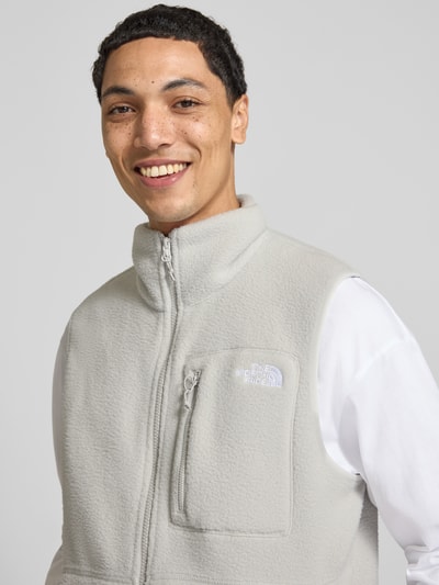 Männermodel trägt Regular Fit Weste mit Logo-Stitching Modell 'Yumiori' von The North Face, hellgrau, Fleece, Nahaufnahme Oberkörper. Herren Weste mit Stehkragen, Napoleontasche und Eingrifftaschen, Rückenlänge 67 cm, Schulterbreite 41 cm, Brustweite 56 cm.