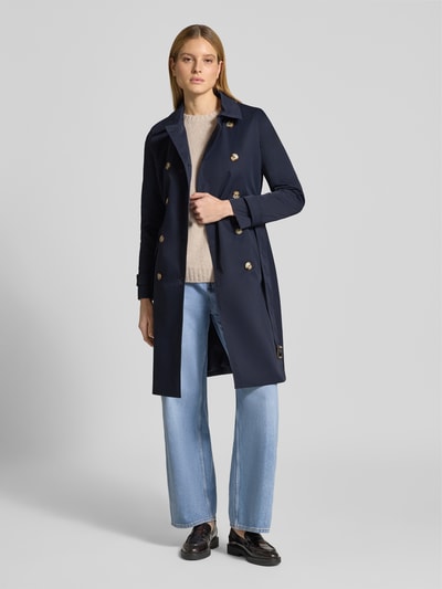 Frauenmodel trägt Trenchcoat mit Ärmelriegeln von Christian Berg Woman Selection in Dunkelblau, doppelreihig, tailliert, Ganzkörperansicht von vorne.
