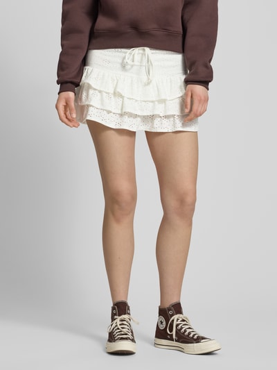 Kobiece model prezentuje Leicht ausgestellter Mini-Skort mit Lochstickerei Modell 'SMILLA' od Only, efekt: jednolity kolor, krój: lekko rozkloszowany, długość mini, faktura: fakturowany wzór, haft angielski, falbany, ściągacz z tunelem, dół obszyty falbaną; widok całej sylwetki z przodu.
