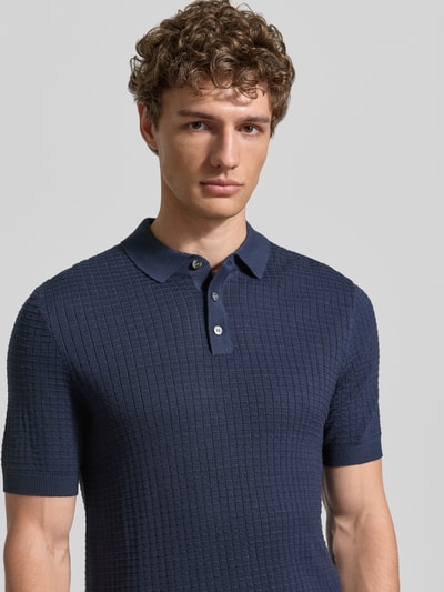 Männermodel trägt Slim Fit Poloshirt in Strick-Optik Modell 'Vanceo' von JOOP! Collection, Reine Baumwolle, marineblau, Nahaufnahme Oberkörper.