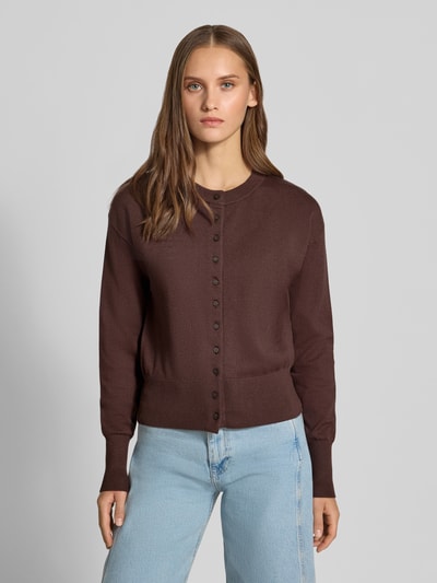 Kobiece modelka nosi brązowy kardigan rozpinany z mieszanki wiskozy Regular Fit Strickjacke aus Viskose-Mix model 'MIO' od ONLY, damski kardigan rozpinany, prosty krój, gładka faktura, jasnoniebieskie dżinsy, widok całej sylwetki od przodu.