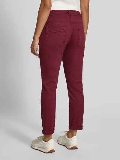 Frauenmodel trägt Relaxed Fit Chino aus Baumwoll-Mix von Tom Tailor in Dunkelrot, glatte Textur, Damen Chino, Ganzkörperansicht Rückansicht.