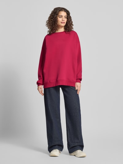 Frauenmodel trägt Oversized Sweatshirt mit Logo-Stitching Modell 'Toast' von OH APRIL in Rot, Baumwoll-Mix, Ganzkörperansicht von vorne.