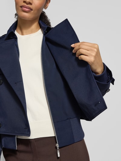 Vrouwenmodel draagt Trenchcoat mit Ärmelriegeln van monari in donkerblauw, regular fit, detailopname bovenlichaam