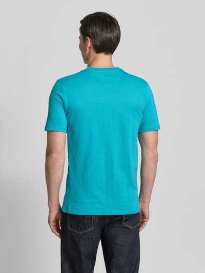 Männermodel trägt Regular Fit T-Shirt mit Logo-Stitching von Scotch & Soda in Türkis, reine Baumwolle, Ganzkörperansicht Rückansicht.