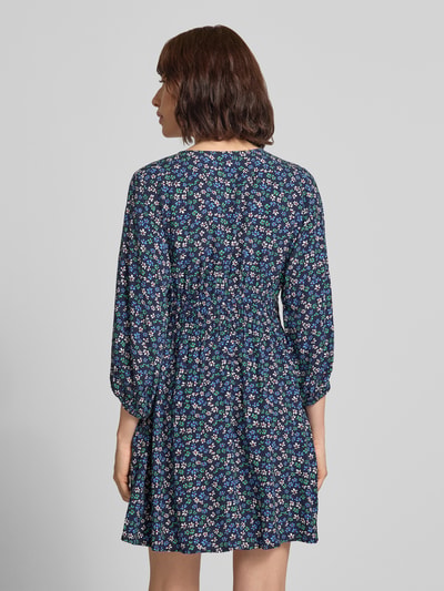 Frauenmodel trägt Minikleid aus reiner Viskose mit floralem Allover-Print von GAP, taillierte Passform, dunkelblau mit buntem Blumenmuster, 3/4-Arm, Rückenlänge 86 cm, Ganzkörperansicht Rückansicht.