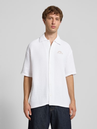 Männermodel trägt Relaxed Fit Freizeithemd mit Strukturmuster von PEGADOR in Weiß, reine Baumwolle, Logo-Stitching, Ganzkörperansicht von vorne.
