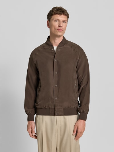 Männermodel trägt blouson aus zijde met ritszakken van bugatti in bruin, regular fit, opstaande kraag, knoopsluiting, geheel vooraanzicht. Ruglengte maat 50: 68 cm, schouderbreedte: 45 cm, borstwijdte: 60 cm, mouwlengte: 67 cm.