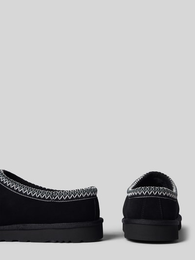 Produktfoto, Hausschuhe aus Leder Modell 'TASMAN II' von UGG in Schwarz, abgerundete Spitze, grobe Naht, 3 cm Absatz, 5 cm Schafthöhe, 15 cm Schaftweite, strukturierte Oberfläche.