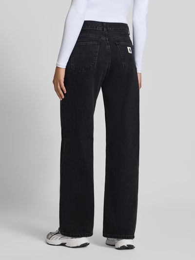 Männermodel trägt Wide Leg Jeans aus reiner bawełna Modell 'Jane' von Carhartt Work In Progress, czarny, 5 kieszeni, zapięcie na guzik i zamek błyskawiczny, Szerokość w rozmiarze 27: 38 cm, Długość wewnętrzna nogawki w rozmiarze 27: 81 cm, Ganzkörperansicht Rückansicht
