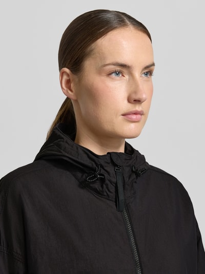 Frauenmodel trägt Jacke mit Kapuze und Zweiwege-Reißverschluss von camel active, czarna, prosty krój, kaptur z ogranicznikami, wpuszczane kieszenie, regulowane zakończenia rękawów, długość tyłu w rozmiarze 36: 67 cm, szerokość ramion w rozmiarze 36: 44 cm, szerokość klatki piersiowej w rozmiarze 36: 63 cm, długość rękawów w rozmiarze 36: 62 cm, tekstura matowa, Nahaufnahme górnej części ciała