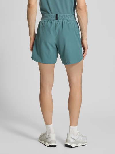 Männermodel trägt Shorts mit Logo und elastischem Bund von NIKE TRAINING in Türkis, Material-Mix mit Stretch, Ganzkörperansicht Rückansicht.