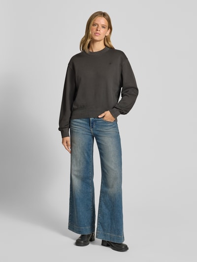 Frauenmodel trägt Relaxed Fit Sweatshirt aus reiner Baumwolle von G-Star RAW in Schwarz, unifarben mit Logo-Schriftzug, Ganzkörperansicht von vorne.
