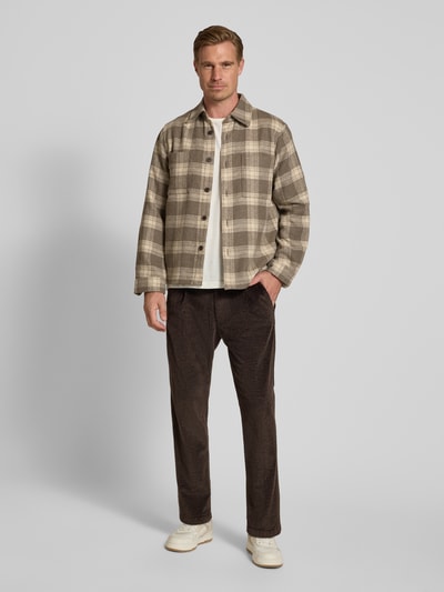 Männermodel trägt Straight Fit Hose aus Baumwoll-Mix Modell 'Chasy' von DRYKORN in Cord-Optik, dunkle Farbe, Kombi aus beige und braun, Gesäßtaschen, Knopf- und Reißverschluss, Minimalstruktur spürbar, Ganzkörperansicht von vorne.