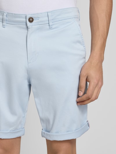 Männermodel trägt Regular Fit Shorts mit Eingrifftaschen Modell 'BOWIE' von Jack & Jones aus Baumwoll-Elasthan-Mix in Hellblau, Nahaufnahme Oberkörper. Bundweite 43 cm, Innenbeinlänge 26 cm, sichtbarer Umschlag, schlicht glatte Oberfläche.