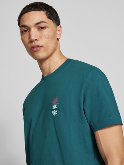 Männermodel trägt Relaxed Fit T-Shirt aus reiner Baumwolle von Marc O'Polo Denim in Petrol, Motiv-Print, Rundhals, Heavy Rough Jersey, Nahaufnahme Oberkörper.