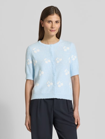 Frauenmodel trägt Slim Fit Strickjacke mit Intarsien Modell 'DOFFY INTARSIA' von Vero Moda in Hellblau mit floralem Allover-Muster, Rundhals, kurzarm, gerippte Abschlüsse, Knopfleiste, Materialverarbeitung Strick, Ganzkörperansicht von vorne.