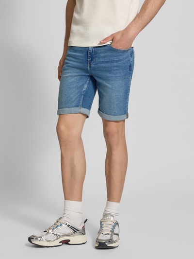 Männermodel trägt Regular Fit Jeansshorts aus Baumwoll-Mix Modell 'PLY' von Only & Sons in Denim-Optik mit Label-Patch, 5-Pocket-Design, Beinabschluss mit Umschlag, Ganzkörperansicht von vorne.