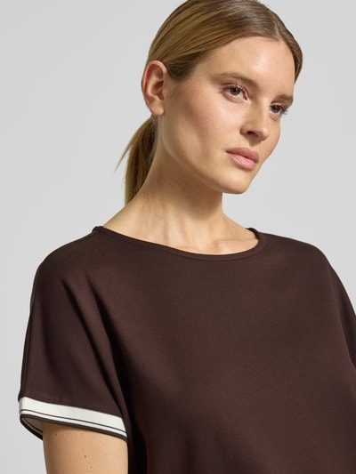 Modelka nosi damski t-shirt z mieszanki wiskozy z dodatkiem streczu model 'Giprep' od OPUS, okrągły dekolt, paski w kontrastowym kolorze, krój relaxed fit, kolor brązowy, tekstura gładka. Zbliżenie na górną część ciała.