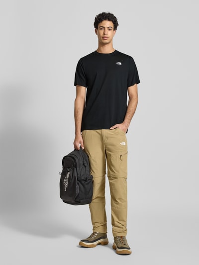 Męski model nosi Regular Fit T-Shirt mit Logo-Stitching od The North Face, czarny, bawełniany, krój regular fit, okrągły dekolt, długość tyłu 70 cm w rozmiarze M, widok całej sylwetki z przodu.