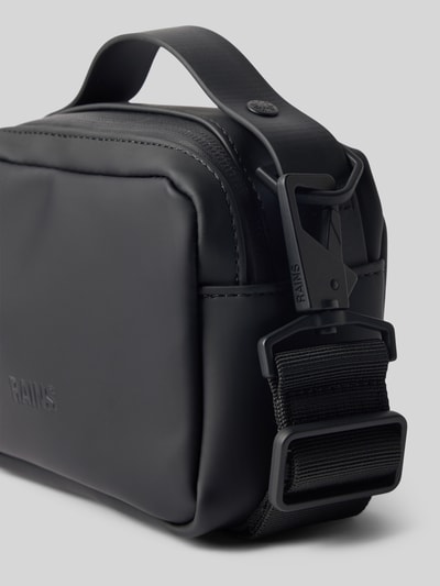 Produktfoto, czarna Handtasche mit Reißverschluss Modell 'BOX BAG MICRO' von RAINS, matowa tekstura, detal zamka, szerokość w rozmiarze 1: 17 cm, długość 12 cm, głębokość 8 cm, pasek 87 cm