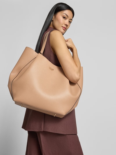 Vrouwenmodel draagt Tote Bag in Leder-Optik Model 'Amorette' van GUESS in beige met logodetail, magneetsluiting, schouderbanden, hoofvak, breedte 44 cm, lengte 37 cm, diepte 11 cm, bandlengte 56 cm, leerlook textuur, ganzekörperaanzicht van achteren.