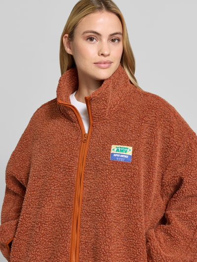 Frauenmodel trägt Oversized Jacke mit Stehkragen Modell 'Hoktown' von American Vintage in Braun, Fleece-Textur, Nahaufnahme Oberkörper.
