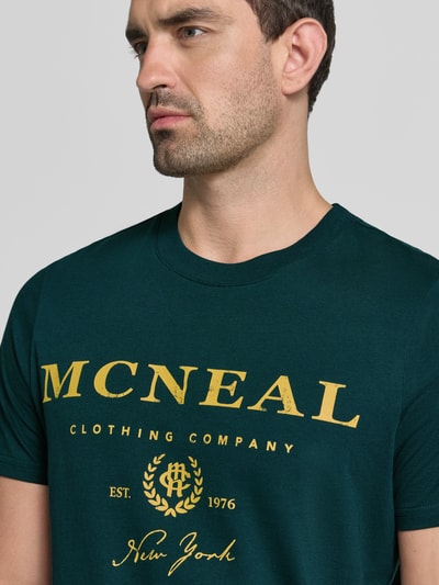 Mężczyzna nosi T-Shirt mit Label-Print und Rundhalsausschnitt von MCNEAL, zielony kolor, bawełna, krój regular fit, długość tyłu 68 cm, nadruk z logo, okrągły dekolt, zbliżenie na górną część ciała