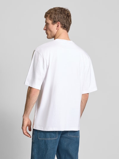 Męski model nosi Oversized T-Shirt mit Logo und Rundhalsausschnitt von The North Face, czysta bawełna, oversize, logo, okrągły dekolt, długość tyłu w rozmiarze M: 73 cm, widok całej sylwetki z tyłu.