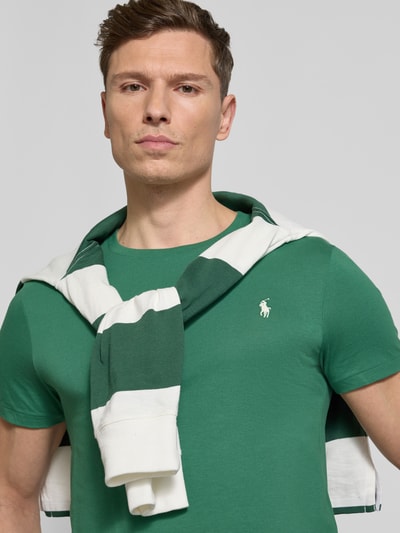 Männermodel trägt Regular Fit T-Shirt aus reiner Baumwolle von Polo Ralph Lauren in Grün mit Logo-Stitching, Nahaufnahme Oberkörper.
