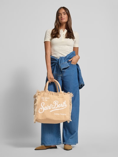 Vrouwenmodel draagt shopper met labelprint en franjes model 'VANITY' van MC2 Saint Barth van puur katoen, draagband, hoofdvak met ritssluiting, breedte 37 cm, lengte 32 cm, diepte 22 cm, schouderbandlengte 48 cm, geheel van voren.