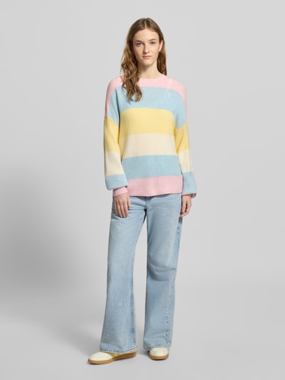 Frauenmodel trägt Regular Fit Strickpullover aus Viskose-Mix Modell 'ATIA' von Only in mehrfarbig gestreifter Optik, Ganzkörperansicht von vorne.