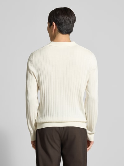 Männermodel trägt Loose Fit Poloshirt aus reiner Baumwolle Modell 'TORINO' von SELECTED HOMME in uni creme mit Rippstruktur, Ganzkörperansicht Rückansicht.