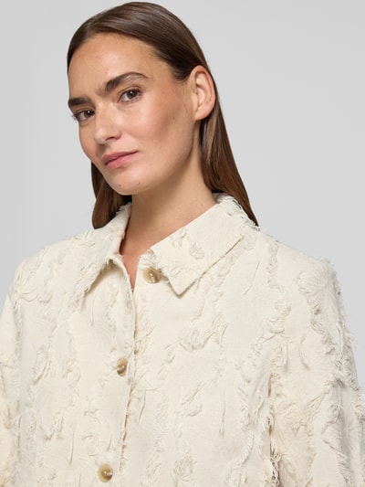 Frauenmodel trägt Regular Fit Jacke aus Viskose-Mix Modell 'Kornelie' von MSCH Copenhagen in Creme mit Umlegekragen, Zierbesatz, Knopfleiste, Leinen-Viskose-Anteil, strukturierte Oberfläche, Nahaufnahme Oberkörper. Rückenlänge 50 cm, Brustweite 48 cm, Ärmellänge 64 cm bei Größe 36.
