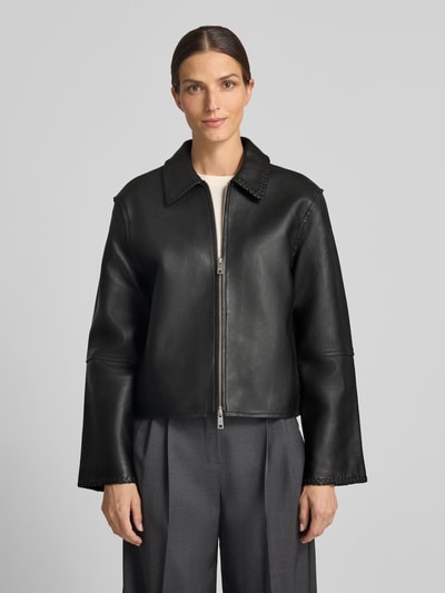 Frauenmodel trägt Relaxed Fit Jacke in Leder-Optik Modell 'SALYLO' von Samsøe Samsøe, schwarz, Umlegekragen, Zweiwege-Reißverschluss, Ganzkörperansicht von vorne.
