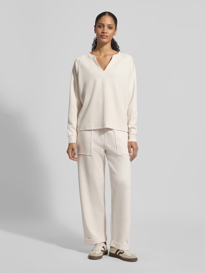 Modelka nosi Relaxed Fit Sweatshirt mit Stretch-Anteil od Christian Berg Woman, kremowy kolor, długi rękaw, V-dekolt, materiał z domieszką modalu, damska bluza, widok całej sylwetki z przodu.